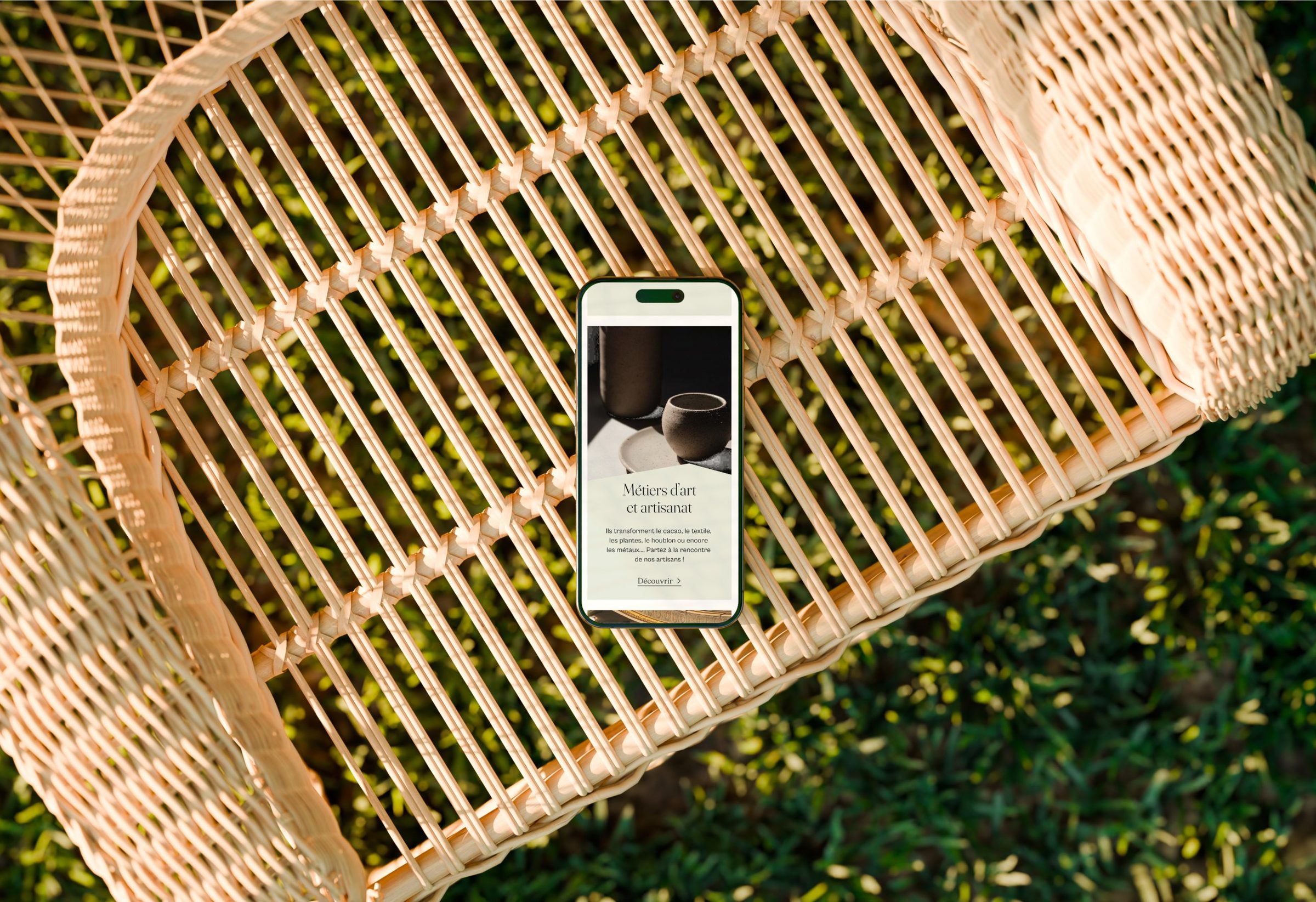 Page Métiers d’art et artisanat sur smartphone posé sur un fauteuil en rotin